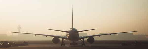 Airplane on runway during hazy sunrise.